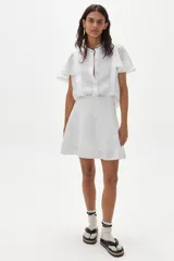 Minifalda blanca de lino con silueta evasé, tiro alto y cierre trasero oculto.