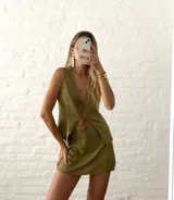 Conjunto de top y falda verde oliva con textura. El top es sin mangas, con escote en V y lazo ajustable en el centro. La falda es corta y ajustada.