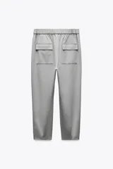 Pantalón tobillero negro de tiro medio con cintura elástica en la espalda, bolsillos delanteros y bolsillos de parche con solapa en la espalda. El bajo está acabado con pinzas y el cierre frontal es con cremallera y botón.