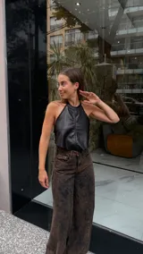 Top halter negro de efecto cuero, ajustado al cuerpo, con detalle de pespunte vertical central y borde festoneado en el escote y sisas.