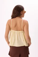 Top color amarillo pálido con breteles finos, escote en V profundo y ajuste frontal con botones.