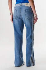 Pantalón de jean azul con paneles en distintos tonos de azul y marrón, corte recto y terminación desflecada.