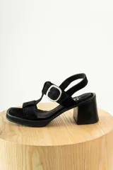 Sandalias negras de charol con tiras entrecruzadas, hebilla dorada y tacón de madera.