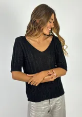 Top de tejido de punto negro con lurex plateado, escote en V y mangas cortas. Tejido con textura acanalada.