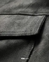 Campera bomber negra de gamuza sintética con cierre frontal, cuello alto, dos bolsillos superiores con solapa, puños y cintura ajustables.