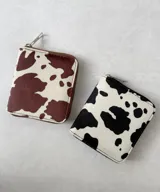 Billetera cuadrada con cierre de cremallera y estampado de vaca en blanco y negro o blanco y marrón.