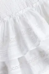 Minifalda blanca de algodón con cintura elastizada y volados escalonados con inserciones de encaje.