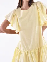 Vestido corto amarillo pastel con mangas cortas con volados y falda con volados.