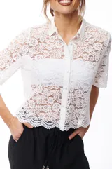 Camisa blanca de encaje con cuello clásico, cierre frontal con botones y mangas cortas.