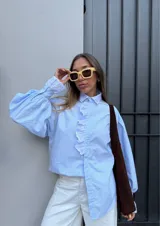 Camisa celeste a rayas verticales con cuello clásico y volados con bordado inglés en el frente y los puños.