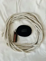 Monedero negro circular con cierre de cremallera y llavero de cinta estampada a rayas.