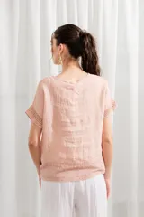 Blusa de lino color rosado, de corte holgado, con cuello redondo y detalle de encaje en ruedo y mangas.