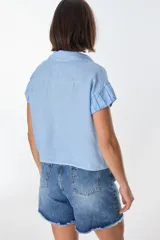 Camisa color beige de lino, con cuello clásico, manga corta con detalle de frunce y bolsillo de parche en el pecho.