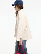 Chaqueta color crema con bordados florales y apliques de pedrería. Tiene cuello camisero, cierre frontal con botones, bolsillos laterales y corte recto.