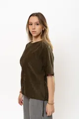 Remera color verde militar de gamuza, con cuello redondo, mangas cortas y detalle de cordones ajustables en el ruedo.