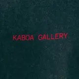 Remera oversize negra con efecto gastado y estampa frontal con el texto 'Kaboa Gallery' en rojo.