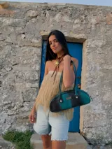 Cartera tipo baguette color marrón con asa corta con detalle de bolitas de madera.