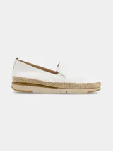 Zapato tipo slip-on de color blanco con elásticos laterales para facilitar el calce. Presenta una suela de plataforma con detalle de yute trenzado en el contorno y base de goma en tonos beige.