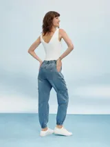 Pantalón de jean gris claro con efecto lavado, corte recto, tiro alto, bolsillos laterales y tobillos ajustados con elástico.