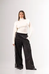 Pantalón negro de tela deportiva con cintura elástica ancha y cordón ajustable. Presenta corte amplio, bolsillos laterales y una franja blanca vertical a lo largo de cada pierna.