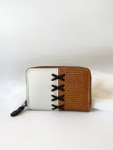 Billetera pequeña de cuero color camel y crudo, con cierre metálico y detalle de cruces bordadas en hilo negro.