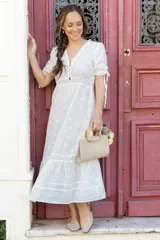 Vestido midi blanco con bordado floral, escote en V con botones, mangas cortas abullonadas con lazos y falda con volantes.