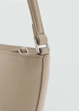 Bolso pequeño color beige, con efecto piel, asa de hombro, diseño ovalado, cierre de cremallera y forro interior.