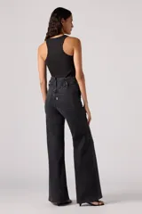 Pantalón de jean acampanado negro de tiro alto con dos botones a la vista.