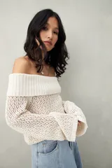 Sweater color crema, tejido de punto calado, con escote off-shoulder y mangas largas acampanadas.