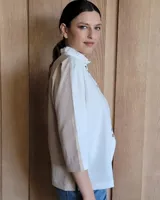 Camisa de manga larga color blanco y beige, con cuello con volados y cierre frontal con botones.