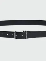 Cinturón negro con textura de piel, hebilla metálica plateada y diseño reversible.
