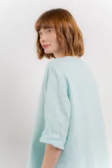 Blusa verde salvia de lino, con escote en V, manga corta y un botón de madera al frente.