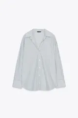 Camisa blanca con rayas verticales azul marino y lurex plateado, de corte recto, cuello solapa, escote en pico y cierre frontal con botones.