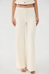 Pantalón de vestir color crudo, de tiro alto, corte recto y textura arrugada. Cuenta con cintura elástica ajustable con cordones.