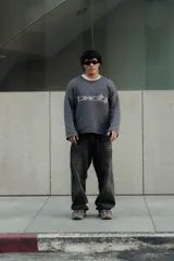 Sweater gris con diseño gráfico en el frente, corte holgado y mangas largas.