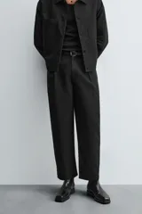 Pantalón negro relaxed fit confeccionado en tejido con algodón, lino y lyocell. Cintura con detalle de pliegues frontales dobles, bolsillos delanteros y traseros. Cierre frontal con cremallera y botón.