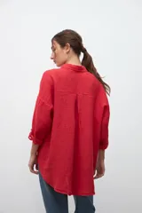 Camisa roja de lino, de corte holgado, con cuello clásico, mangas 3/4 y cierre frontal con botones.