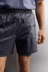 Shorts deportivos confeccionados en tejido técnico ligero con efecto arrugado y forro interior. Cuenta con cintura elástica ajustable con cordón, bolsillos laterales con cierre de cremallera, bajo con aberturas laterales y logo estampado en la pierna.