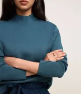 Sweater negro de punto con cuello redondo, puños y ruedo acanalados. Incluye cuello, puños y ruedo de camisa celeste a rayas.