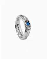Anillo plateado con textura y detalle de estrella con piedra azul.