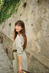 Vestido camisero midi color verde claro, con cuello solapa, escote pico, manga larga remangada con trabilla y botón, bolsillos delanteros de plastrón, cintura elástica, cierre frontal con botones y cinturón de rafia trenzada con hebilla redonda.