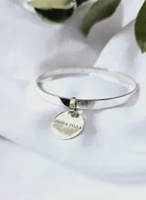 Pulsera rígida plateada con dije redondo grabado con la fecha "28.04.2024".