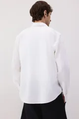 Camisa blanca de lino y algodón con cuello inglés, tapeta clásica y canesú en la espalda. Modelo de manga larga con bolsillo superior abierto, cierre ajustable de botón en los puños y tapeta con botón. Bajo redondeado. Corte estándar.