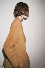 Blazer de cuero color marrón, con cuello solapa de muescas y manga larga. Bolsillos delanteros ocultos en costura y cierre frontal con botones.