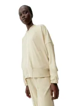 Campera tipo bomber color beige, de corte holgado y mangas murciélago, con cierre frontal y bolsillos laterales. Confeccionada en tejido Peach_T extra suave, compacto y elástico.