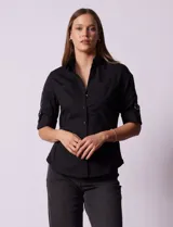 Camisa negra de algodón con cuello clásico, escote en V y mangas 3/4 con trabillas y lazos. Tiene dos bolsillos con solapa en el pecho y cierre frontal con botones.