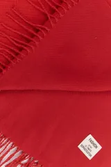 Bufanda rectangular color rojo con flecos en los extremos.