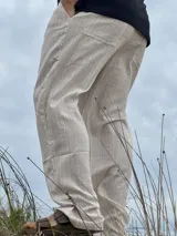 Pantalón de lino beige y crudo a rayas, de corte ancho y relajado.