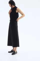 Pollera midi negra con leve brillo y caída suave. Modelo de tiro alto con elástico oculto en la cintura y leve vuelo en el bajo.