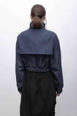 Campera cropped de inspiración deportiva, color azul marino, con cuello alto, cierre frontal a tono, bolsillos funcionales y puños elastizados. Confeccionada en tela campera repelente al agua, con interior de micropolar.
